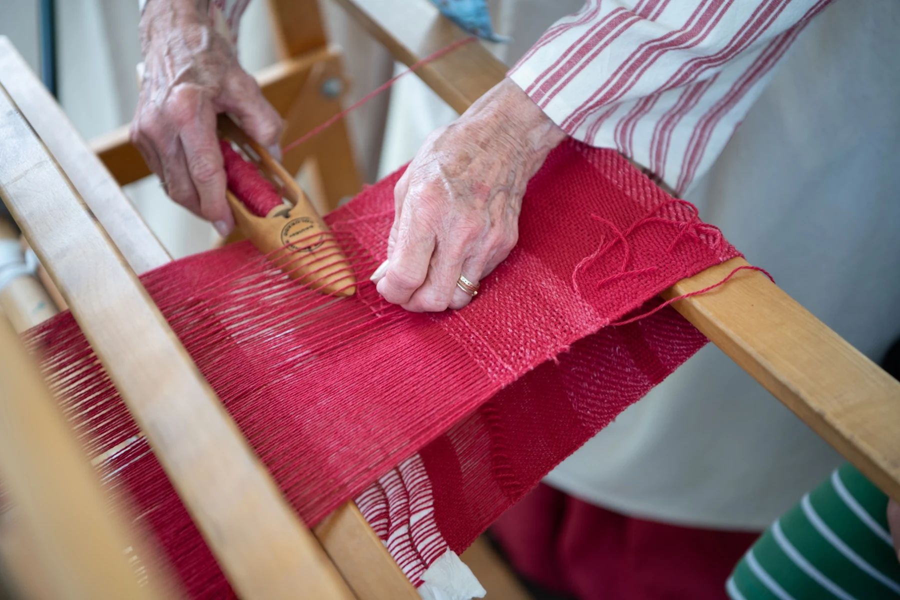 A close view of a weaving demonstration using red thread.