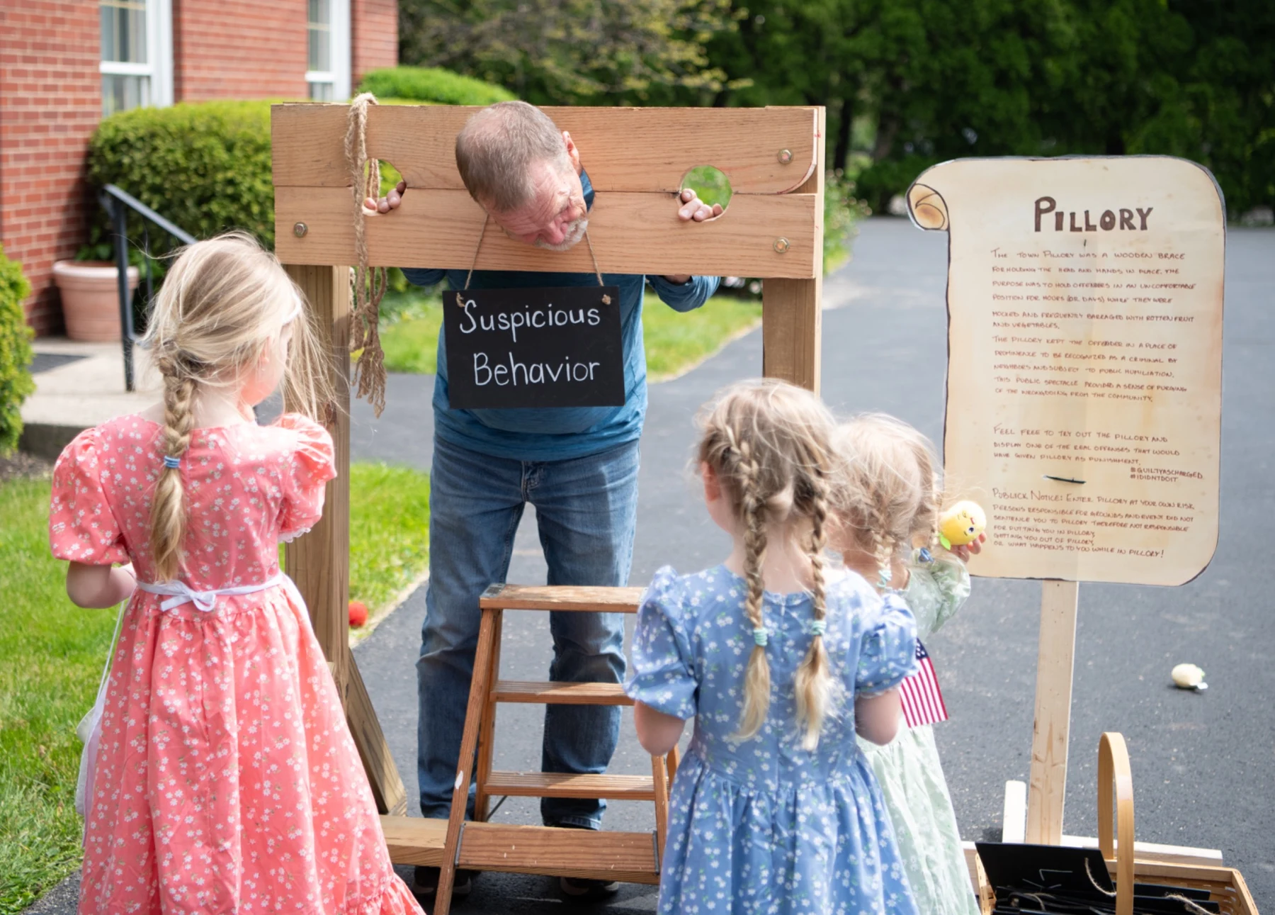 Young visitors look on as a participant tries the demonstration pillory.