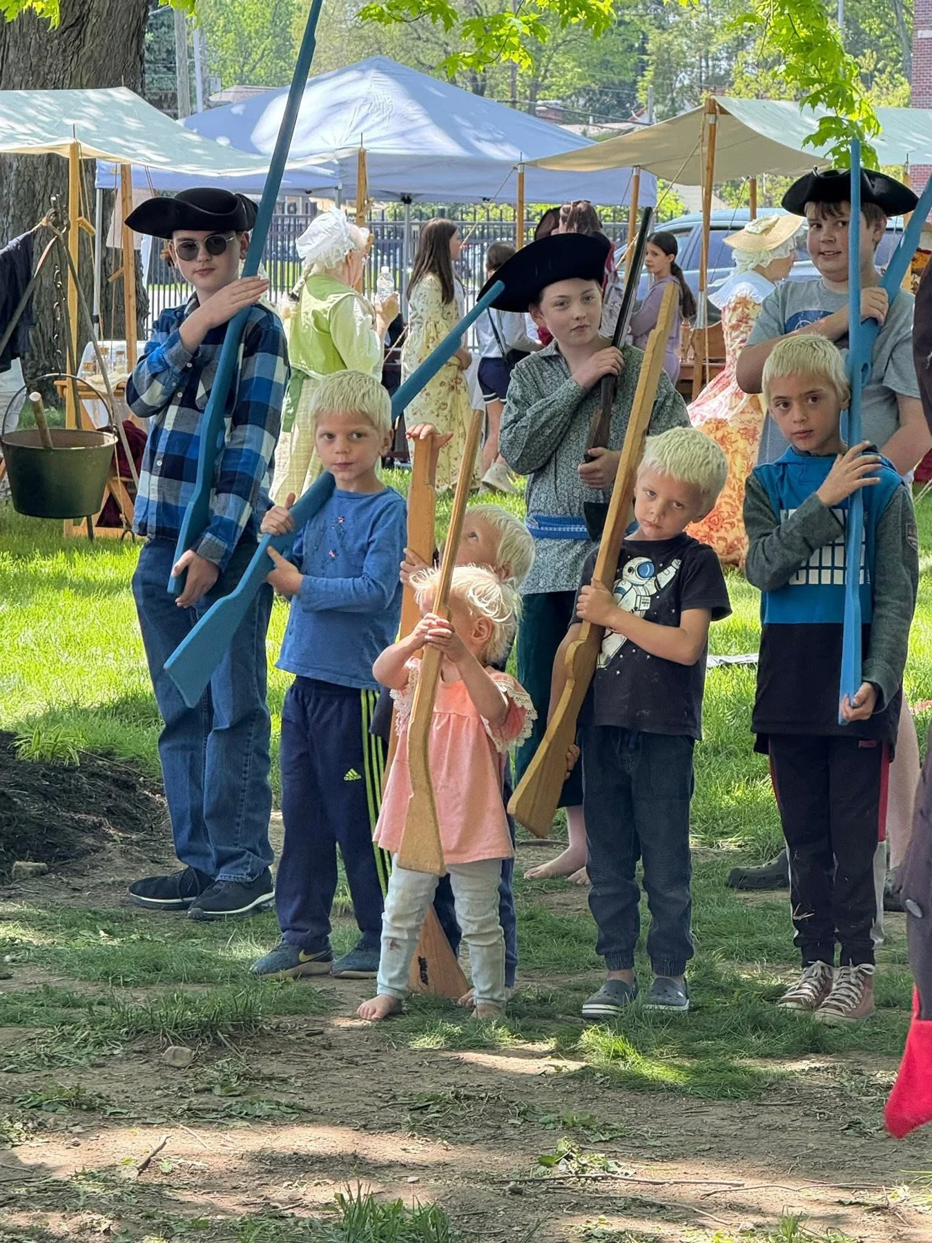Children and interpreters gather with wooden practice muskets.