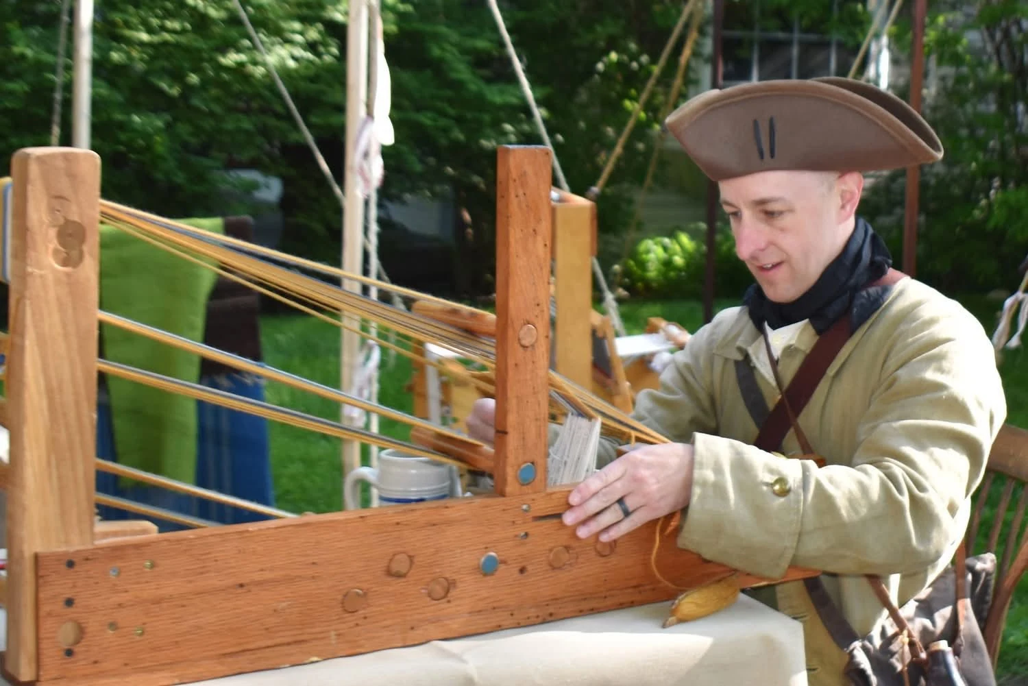 An interpreter demonstrates weaving on a wooden loom.