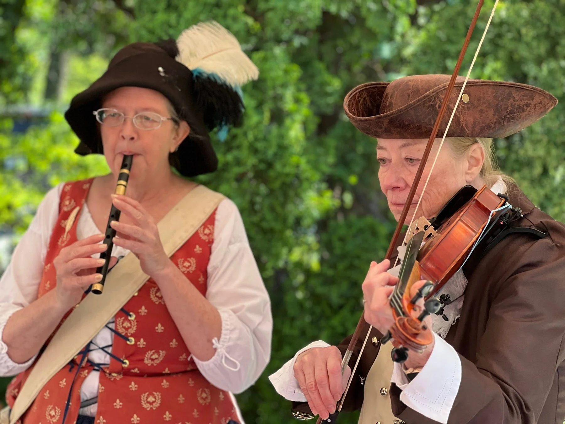 Two costumed musicians play a wind instrument and a violin.