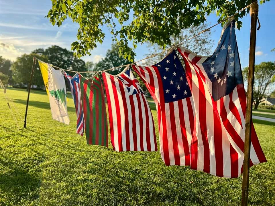 A row of historical American flags displayed outdoors.