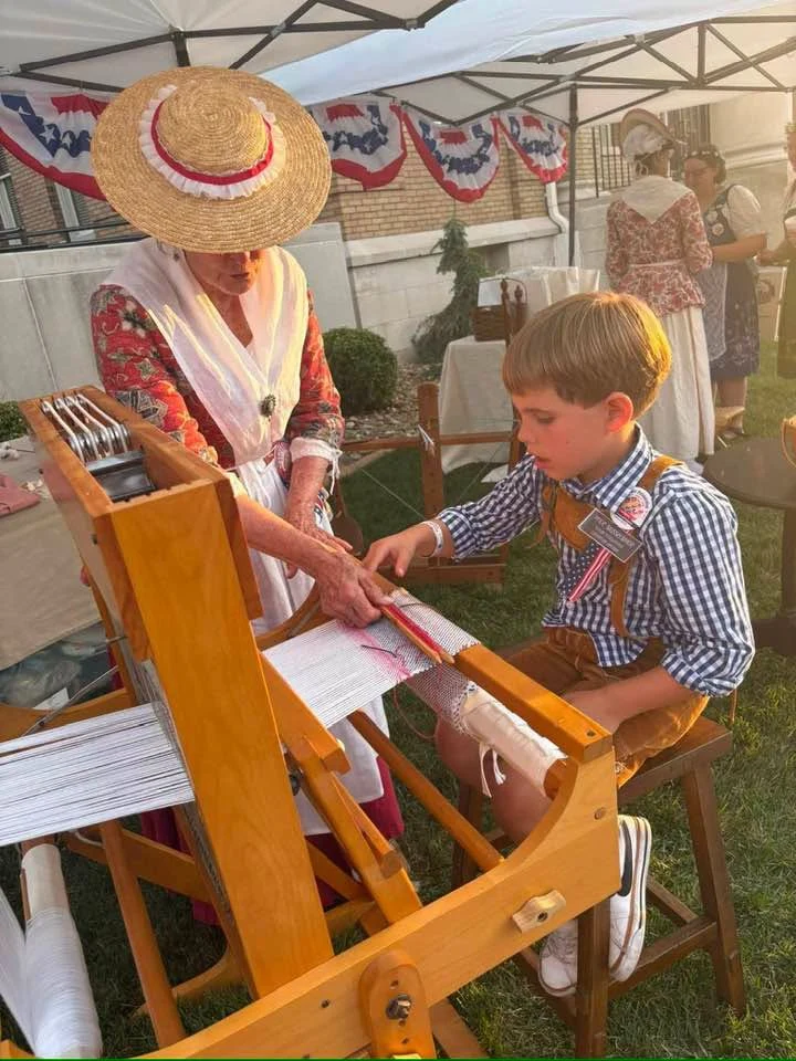 A child explores a wooden loom with an interpreter.