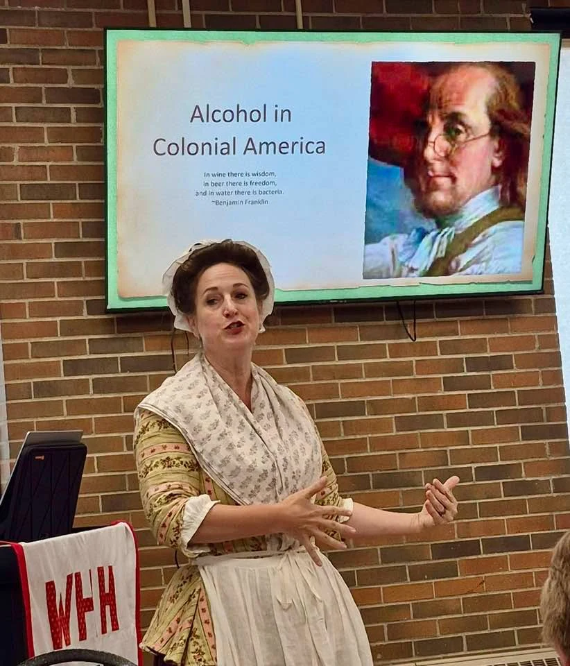 Jen presents beside a slide titled Alcohol in Colonial America.