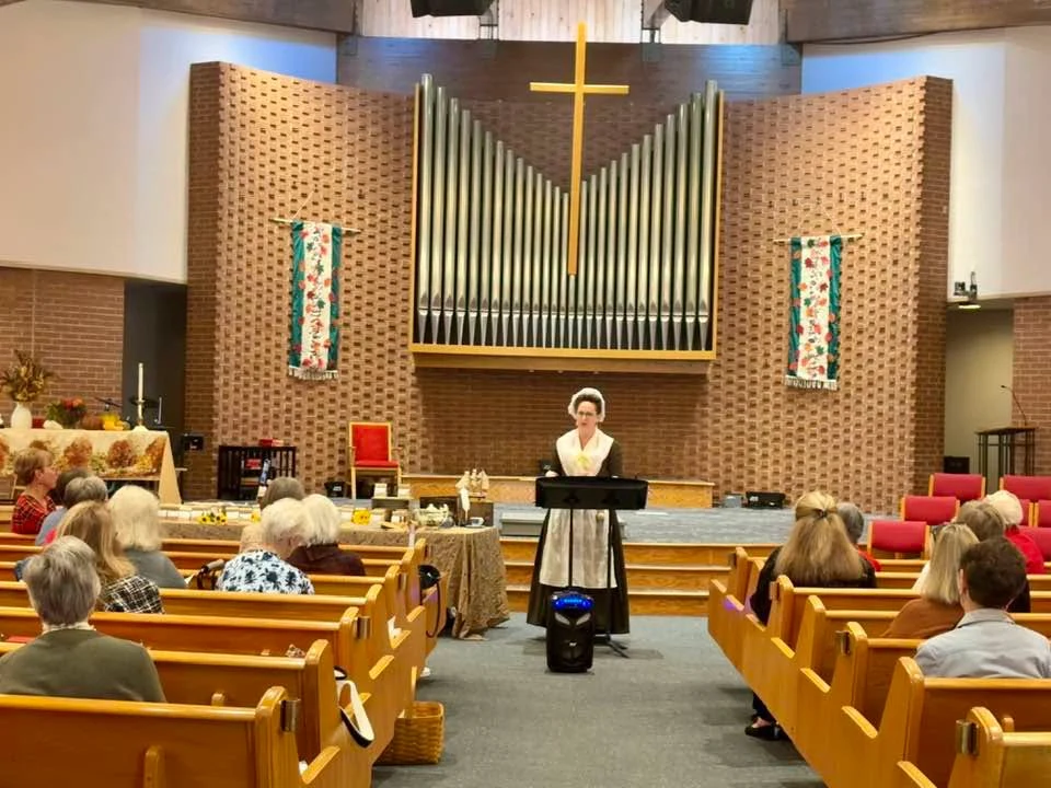 Jen addresses an audience seated in a church.